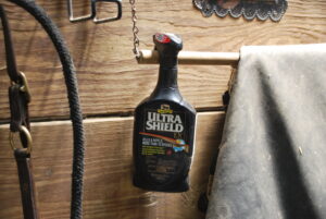 A bottle of fly spray hanging on a horse's stall