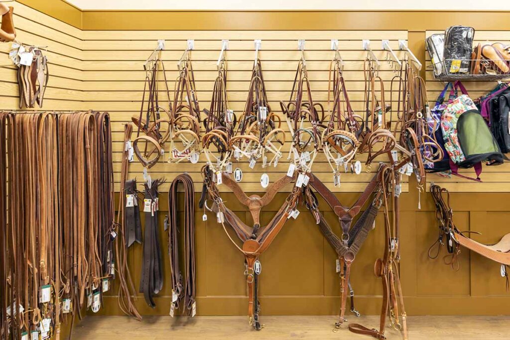 An equine tack shop display with western bridles, breast collars, and reins