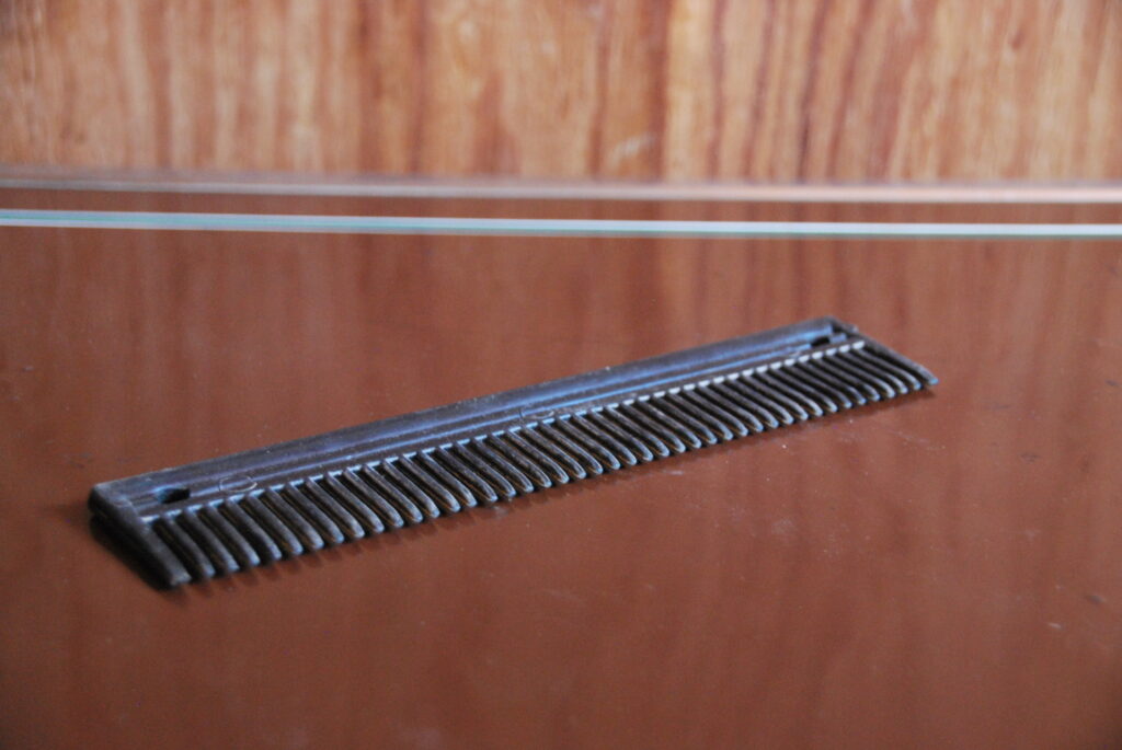 A black comb for a horse sits on a tack trunk