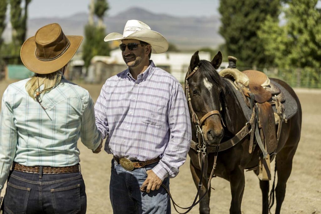 A man sells a horse to a woman and they shake hands