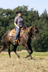 a woman rides a western horse at the lope