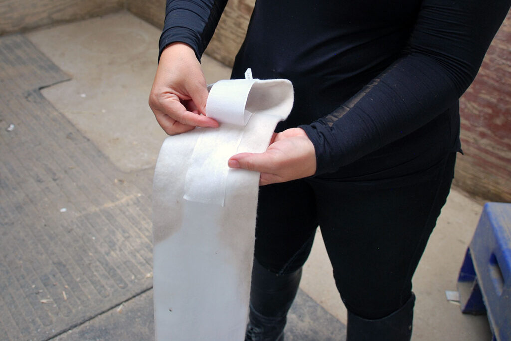 close-up image of someone rolling up a white polo wrap for a horse's leg