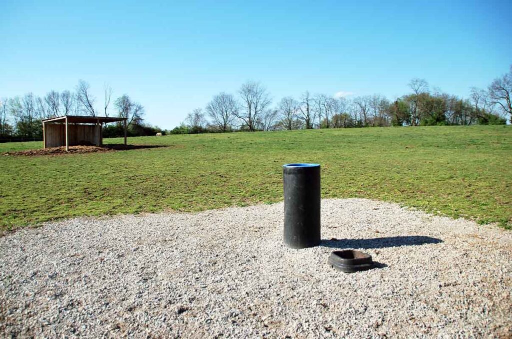 A high-traffic pad surrounds an automatic waterer in a safe horse pasture