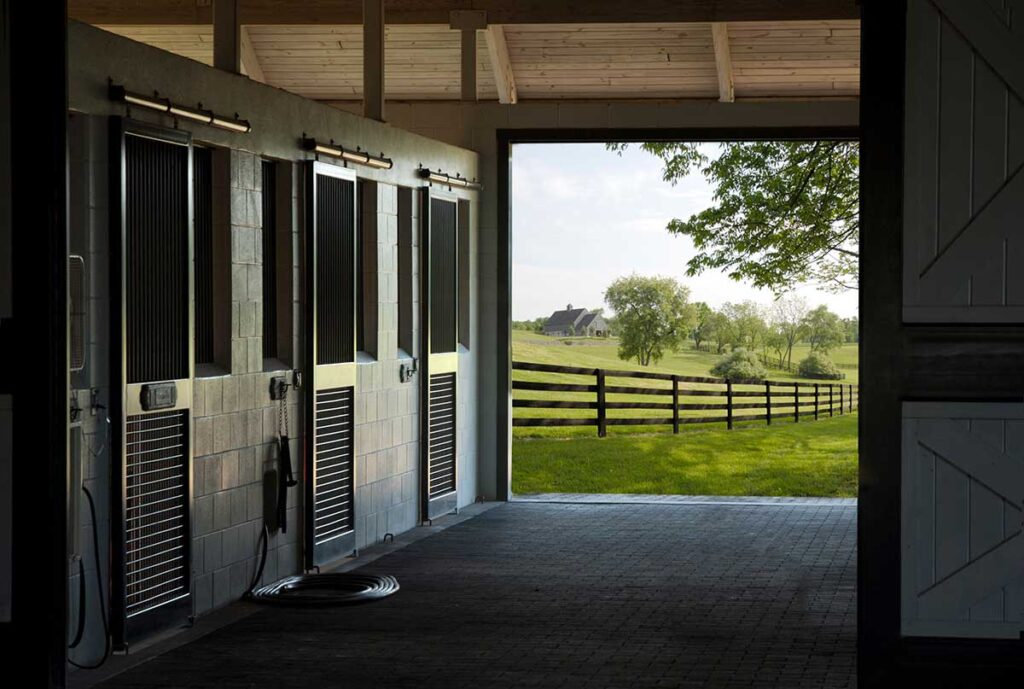 a clean and tidy horse barn aisle with pasture in the background. How to fireproof your horse barn.